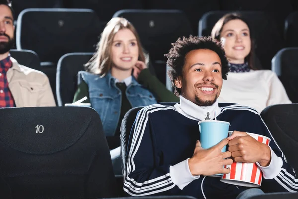 Selective focus of smiling african american man watching movie in cinema — Stock Photo