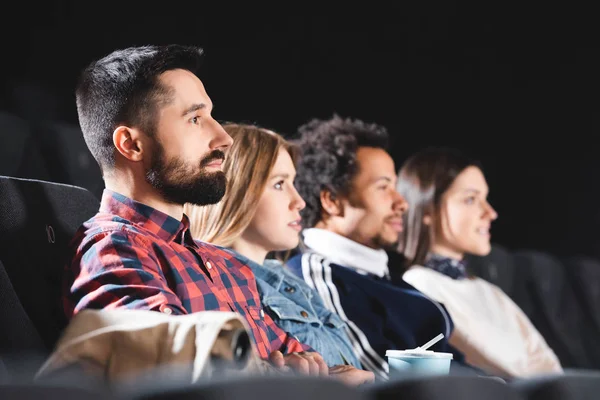 Focus sélectif d'amis multiculturels regardant des films au cinéma — Photo de stock