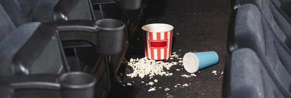 Plano panorámico de palomitas de maíz y taza de papel con soda en el suelo en el cine - foto de stock