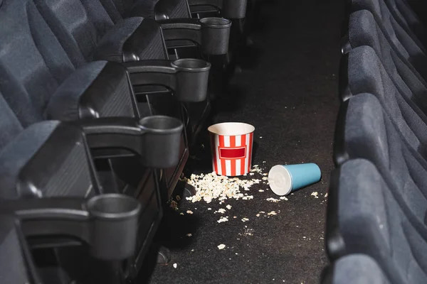 Foco seletivo de pipoca e xícara de papel com refrigerante no chão no cinema — Fotografia de Stock
