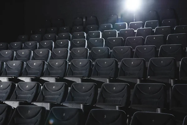 Cinema hall with rows of grey seats in darkness — Stock Photo
