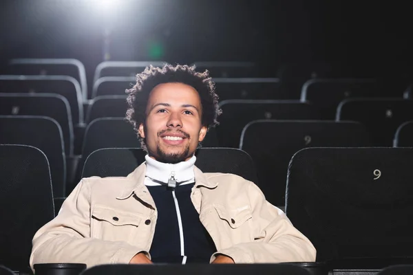 Sorridente e bonito afro-americano assistindo filme no cinema — Fotografia de Stock