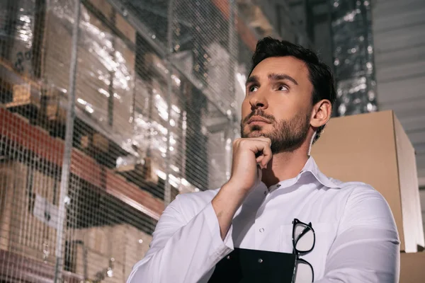 Thoughtful storekeeper looking away while standing in warehouse — Stock Photo