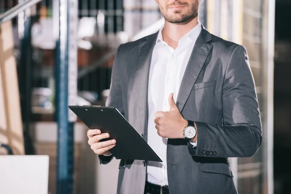 Abgeschnittene Ansicht des Geschäftsmannes in formeller Kleidung mit Klemmbrett im Lager — Stockfoto