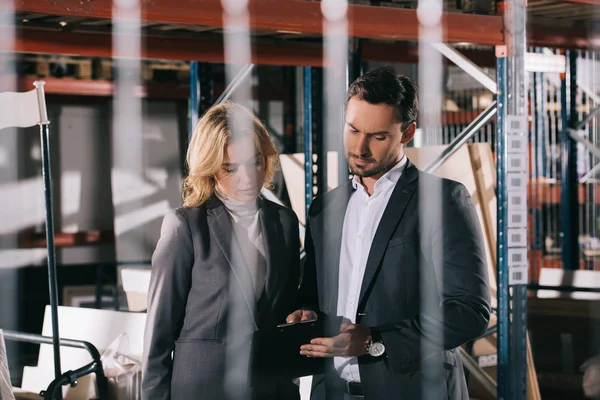 Selective focus of concentrated businesspeople using calculator in warehouse — Stock Photo