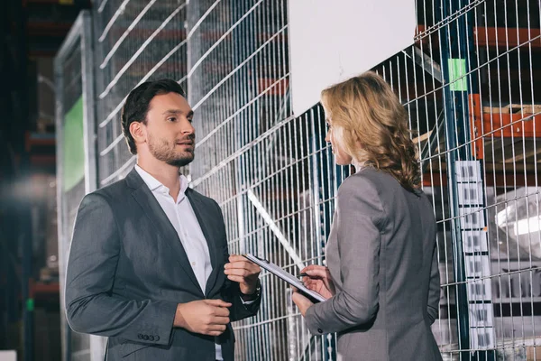 Confident business partners talking while standing in warehouse — Stock Photo