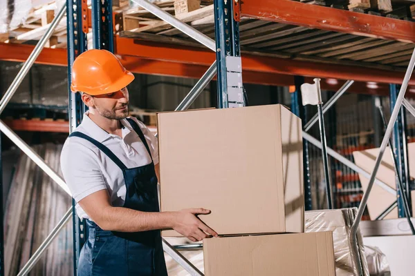 Travailleur d'entrepôt prenant boîte en carton de la pile dans l'entrepôt — Photo de stock