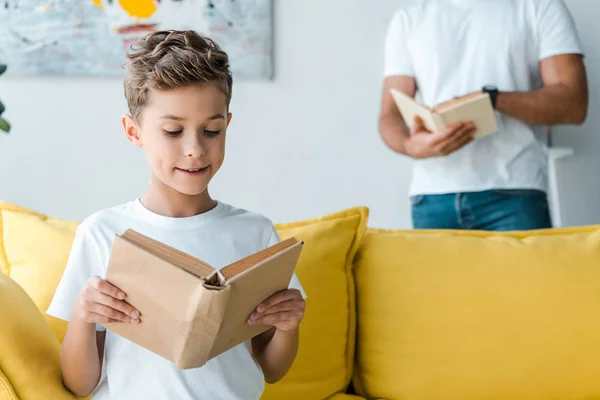 Vista recortada de padre e hijo sosteniendo libros en casa - foto de stock