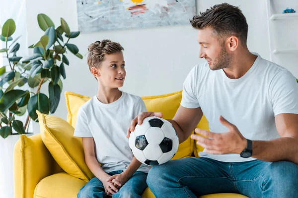 Красивый отец держит футбол и смотрит на сына — стоковое фото