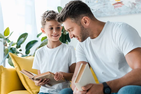 Messa a fuoco selettiva di felice padre e figlio in possesso di libri — Foto stock