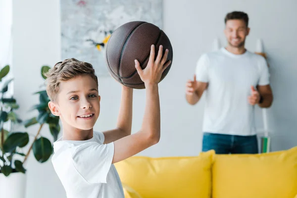 Enfoque selectivo de niño feliz con baloncesto cerca del padre - foto de stock