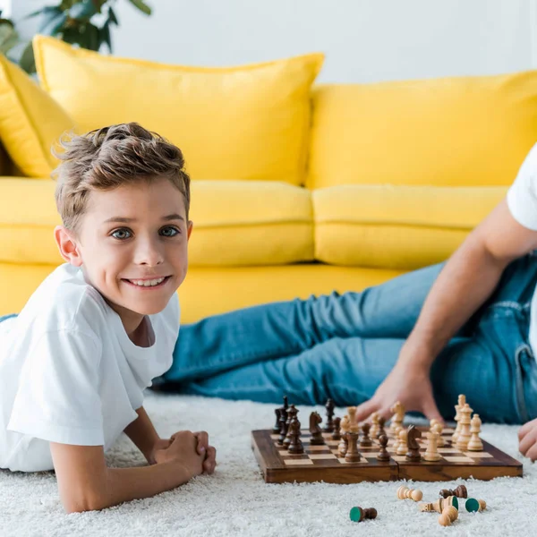Обрезанный вид отца и сына, играющих в шахматы на ковре — стоковое фото