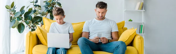 Plan panoramique de père et fils à l'aide de gadgets à la maison — Photo de stock