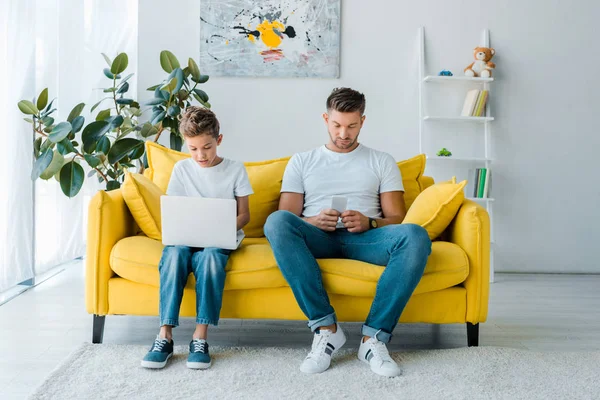 Handsome father and son using gadgets at home — Stock Photo