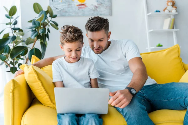 Glücklicher Vater und Sohn schauen zu Hause auf Laptop — Stockfoto