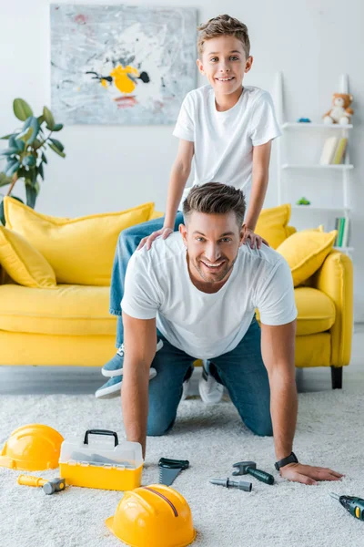 Feliz hijo y hermoso padre jugando cerca de caja de herramientas de juguete - foto de stock