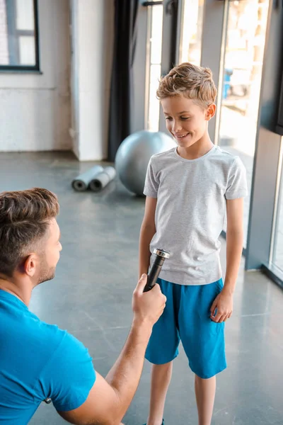 Selective focus of father giving dumbbell to happy son — Stock Photo