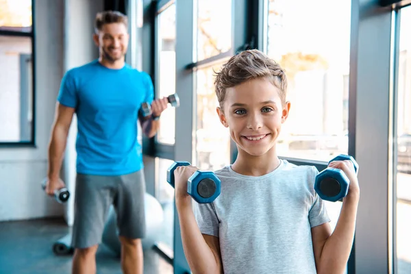 Selective focus cute kid exercising with dumbbells near father — Stock Photo