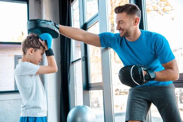 Glücklicher Vater und süßer Sohn in Boxhandschuhen beim Training im Fitnessstudio — Stockfoto