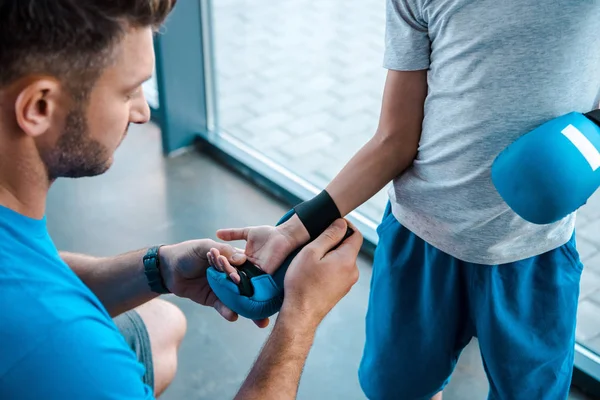 Selective focus of handsome father wearing boxing glove on son — Stock Photo