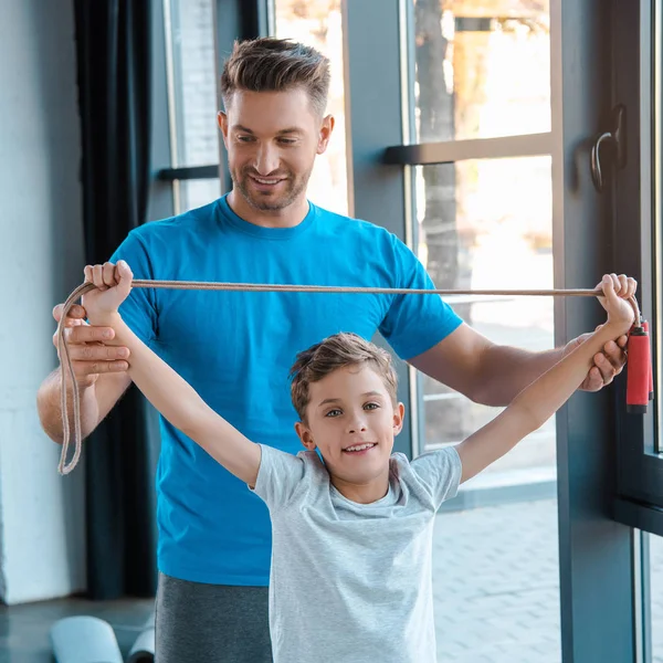 Красивый отец трогает руки сына скакалкой в спортзале — стоковое фото