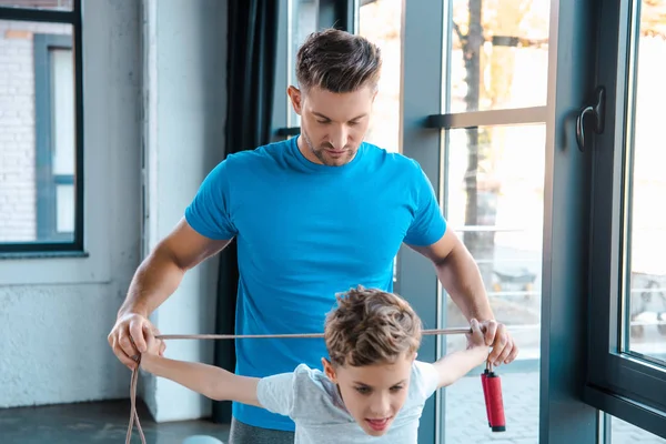 Messa a fuoco selettiva del padre e del bambino bello che tengono la corda di salto in palestra — Foto stock