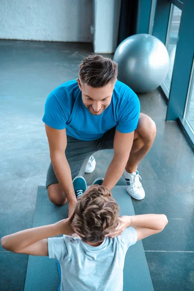 Overhead view of handsome father looking at son exercising on fitness mat — Stock Photo