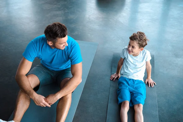 Vista aérea de lindo niño y padre mirándose en el gimnasio - foto de stock