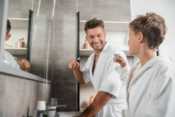 Selektiver Fokus des glücklichen Vaters, der seinen Sohn mit der Zahnbürste betrachtet — Stockfoto