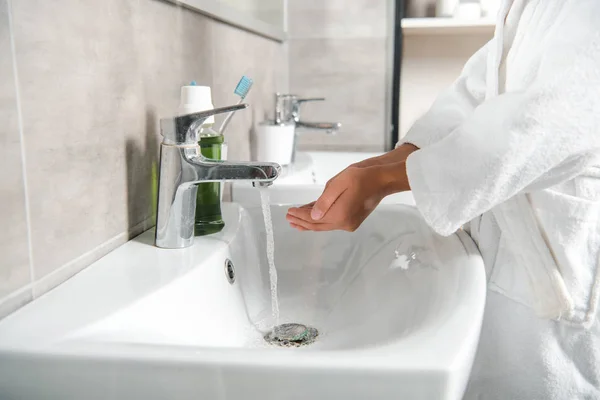 Обрезанный вид человека в белой ванне с чашечками рук возле крана с водой — стоковое фото
