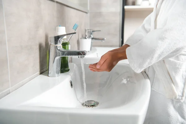 Cropped view of man in white bathtub with cupped hands near faucet with water — Stock Photo