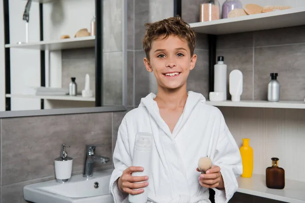 Cheerful kid holding shaving brush and can with shaving foam — Stock Photo