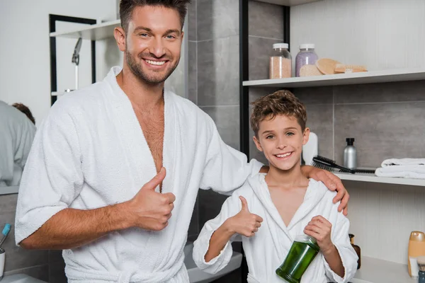 Happy father and cheerful son showing thumbs up in bathroom — Stock Photo