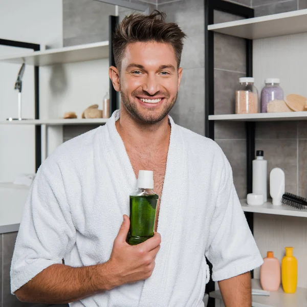 Cheerful man holding bottle with green mouthwash — Stock Photo