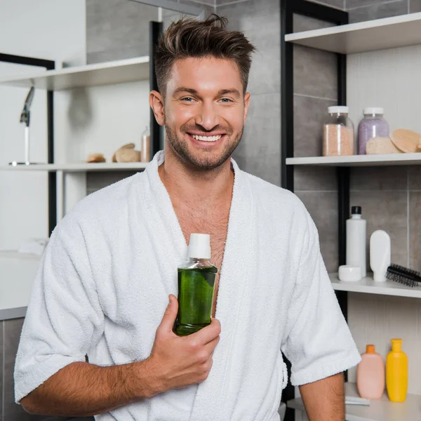 Homem alegre segurando garrafa com bochecho verde — Fotografia de Stock