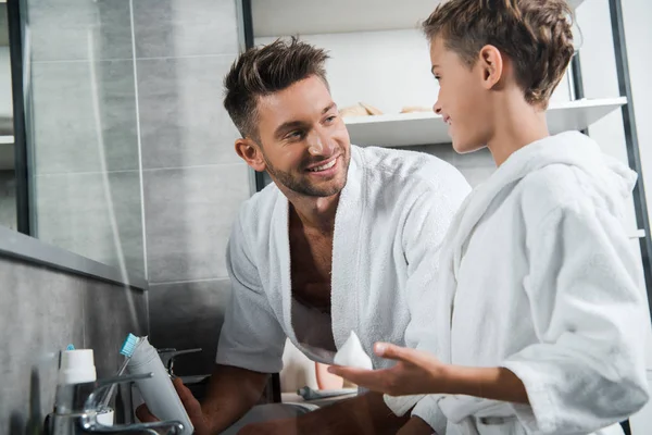 Enfoque selectivo de padre mirando hijo con espuma de afeitar en la mano - foto de stock