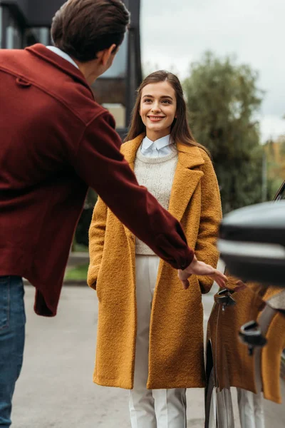 Taxi driver opening door of auto and looking at smiling woman — Stock Photo