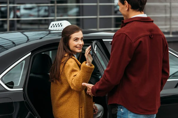 Taxi driver opening auto door for smiling woman — Stock Photo