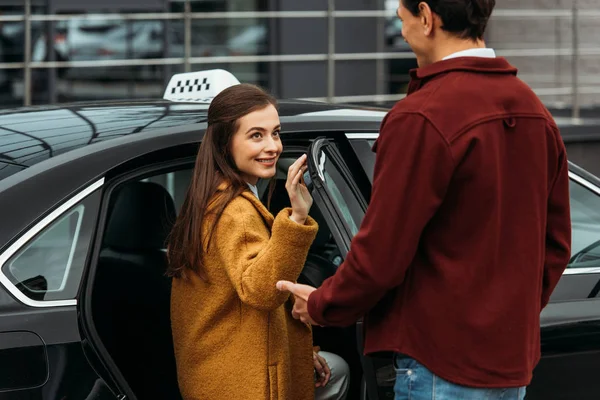 Taxi conductor de apertura de la puerta automática para la mujer sonriente - foto de stock