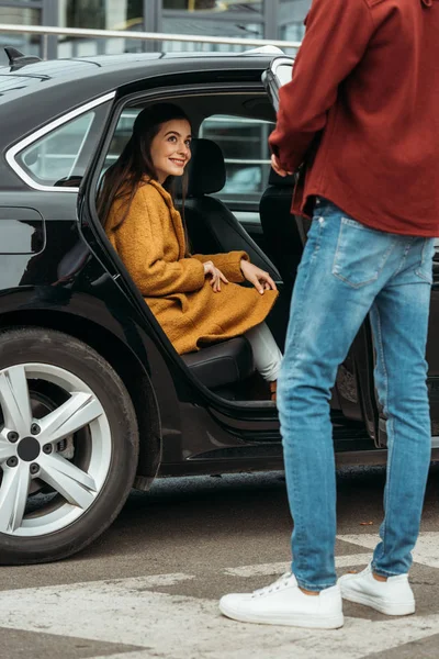 Taxi conductor abriendo la puerta del coche a la joven sonriente - foto de stock
