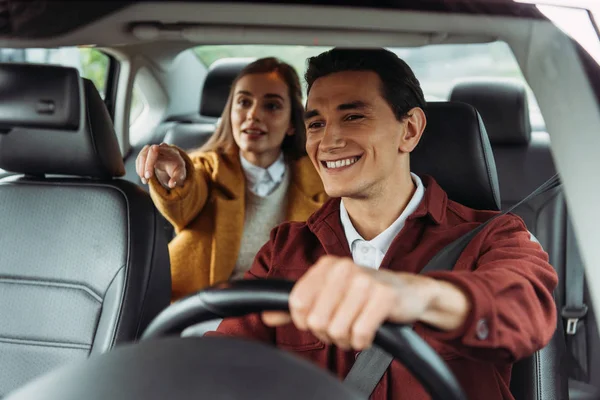 Smiling taxi driver with woman passenger pointing on road — Stock Photo