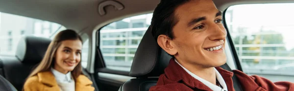 Selective focus of smiling taxi driver and woman on back seat of car, panoramic shot — Stock Photo