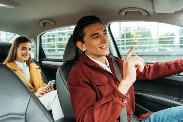 Chauffeur de taxi souriant et passager avec smartphone en voiture — Photo de stock