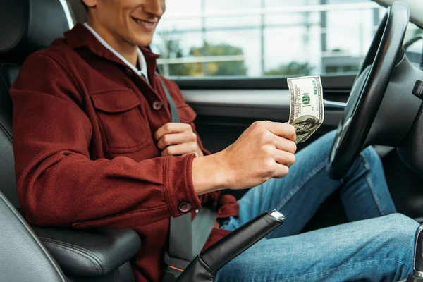 Vue recadrée d'un chauffeur de taxi souriant tenant un billet en dollar — Photo de stock