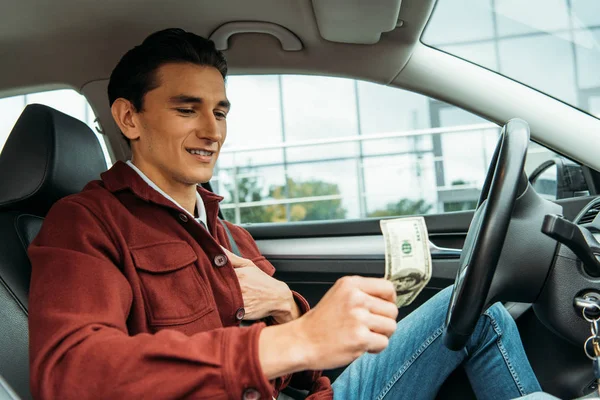 Homme chauffeur de taxi tenant billet en dollar dans la voiture — Photo de stock