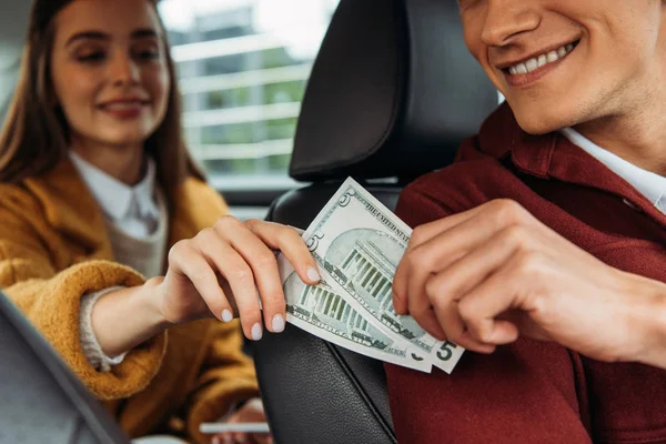 Concentration sélective du passager donnant des billets en dollars au chauffeur de taxi — Photo de stock