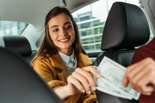 Concentration sélective de la femme souriante donnant de l'argent au chauffeur de taxi — Photo de stock