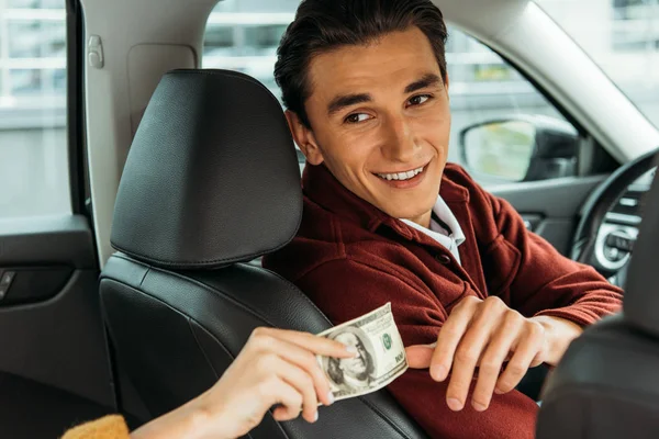 Sonriente taxista tomando efectivo de la mano de la mujer - foto de stock