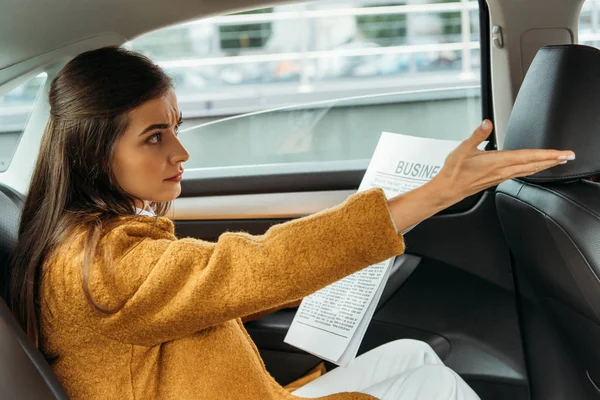 Passeggero donna scontento con giornale sul sedile posteriore del taxi — Foto stock