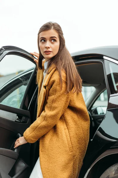 Mujer joven bajándose del taxi y mirando hacia otro lado - foto de stock